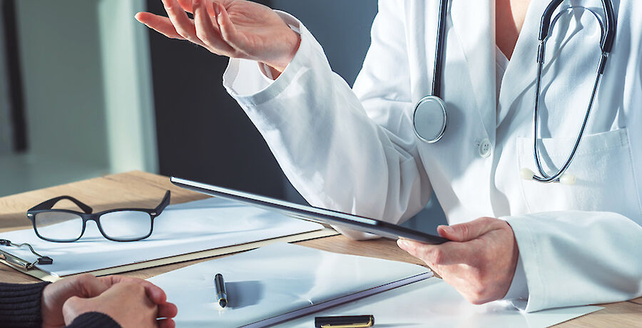 Arzt mit Tablet bespricht sich mit Patient:in.